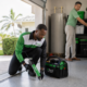 In Touch Pest Control technician sealing a garage threshold while a homeowner organizes storage