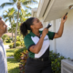 South Florida roofline rodent exclusion inspection Black Caribbean pest-control technician inspecting a South Florida soffit for rodent entry gaps
